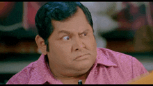 a man wearing a pink shirt making a funny face