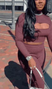 a woman wearing a purple top and pants is walking down the street