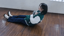 a woman in a green jacket is laying on the floor with her legs crossed