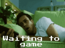 a man laying on a couch with the words " waiting to game " on the screen