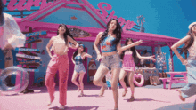a group of girls are dancing in front of a pink building that says ' shack ' on it