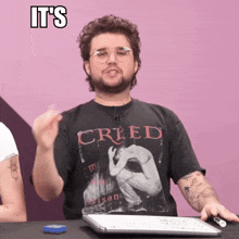 a man wearing a creed t-shirt is making a gesture