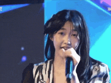 a young girl is singing into a microphone while wearing a zebra print shirt .
