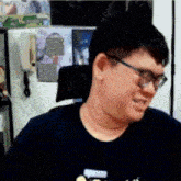 a man wearing glasses and a blue shirt is sitting in a chair