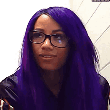 a woman with purple hair and glasses is wearing a black jacket .
