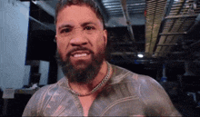 a man with a beard is wearing a chain around his neck and has a tattoo on his chest