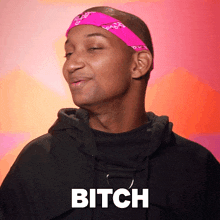 a man wearing a pink headband has the word bitch on his chest