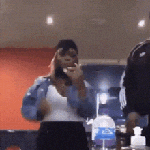 a woman is standing in a room with a bottle of water in the background .