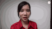 a woman in a red shirt is looking at the camera with a white background behind her that says ' ehhh '