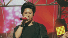 a man singing into a red microphone with the letter d visible in the corner