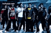 a group of young men are standing next to each other on a street in the rain .