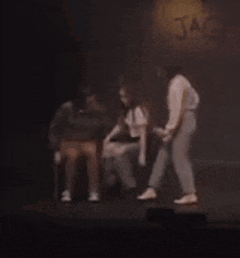 a group of people are standing on a stage in front of a sign that says jackie .