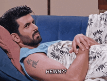 a man with a tattoo on his arm is laying on a couch with the words heinn written above him