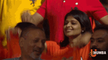 a woman in an orange shirt with the word mumbai on the bottom right