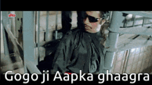 a man wearing sunglasses is sitting on a staircase with the words gogo ji aapka ghaagra on the bottom .