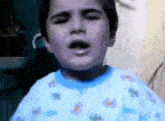 a young boy wearing a blue shirt with animals on it is crying