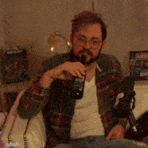 a man in a plaid shirt is drinking from a bottle with a monopoly board in the background