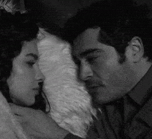 a black and white photo of a man and woman laying on a bed
