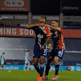 two soccer players on a field with a h-e-b sign behind them