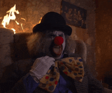a clown with a red nose is sitting in a chair
