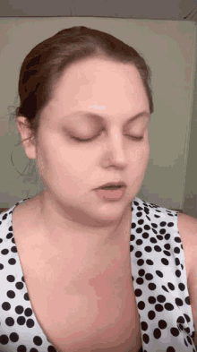 a woman with her eyes closed wearing a polka dot top
