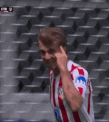 a man in a red and white striped shirt is talking on his phone