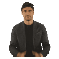 a man in a suit and black shirt is clapping his hands together