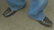 a pair of black shoes and blue jeans on a person