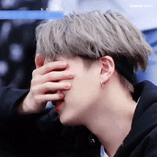 a close up of a person covering their face with their hand