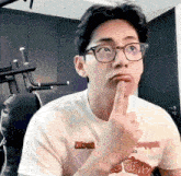 a man wearing glasses and a white t-shirt is making a funny face .