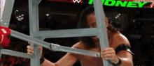 a wrestler is holding a ladder in a ring with the word money on the screen behind him .
