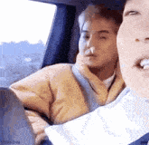 a man is sitting in a car with his nose in his hand .