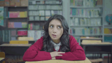 a woman in a red sweater sits at a desk