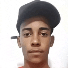 a young man is wearing a black hat and looking at the camera .