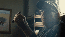 a man wearing glasses and a baseball cap holds a cigar