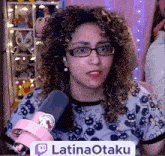 a woman with curly hair is wearing glasses and holding a microphone with a sign that says latinaotaku