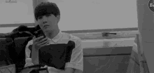 a black and white photo of a man holding a cell phone in his hand .