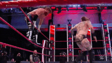 two men are wrestling in a wrestling ring and one of them is jumping in the air .