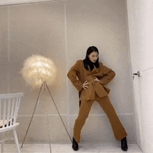 a woman in a brown suit is dancing in a room next to a lamp and a chair .