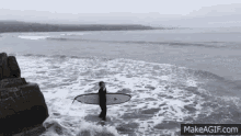 a man is carrying a surfboard in the water .