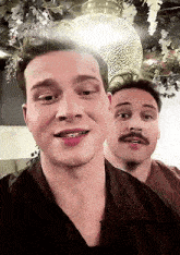 a man with a mustache is standing next to another man .