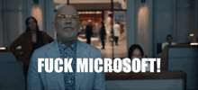 a man in a suit says fuck microsoft in front of a crowd