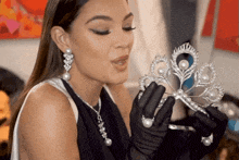 a woman in black gloves is holding a tiara