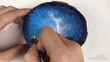 a person is holding a piece of wood with a painting of a night sky on it