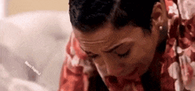 a woman is crying while sitting on a couch and covering her face with her hands .