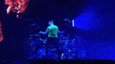 a man in a green shirt is singing into a microphone on stage