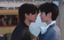 two young men are looking at each other 's faces while standing next to each other .
