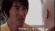 a man in a yellow shirt is talking to another man with chinese writing on his face