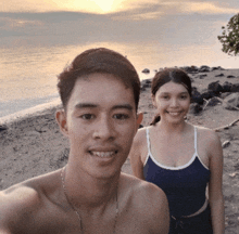 a man and a woman are posing for a photo on the beach