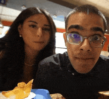 a man and a woman are posing for a picture and the man has glasses on